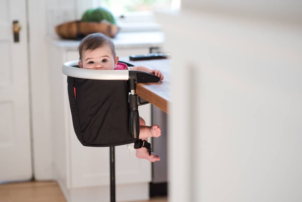 baby in highchair attached to table