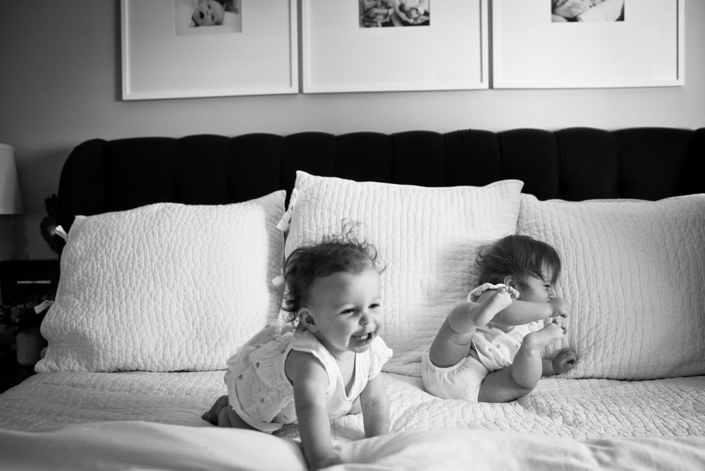twin girls playing on a bed