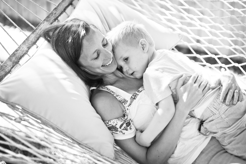 mom snuggles with boy on hammock