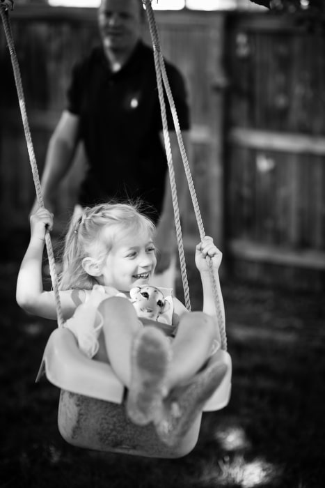 litlte girl in swing with dad pushing