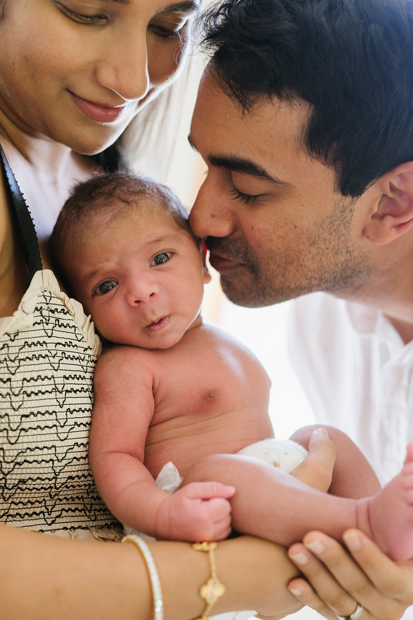 newborn portrait with parents kissing baby